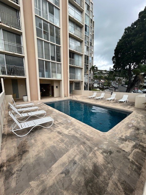 A pool area with chairs and a building in the background.